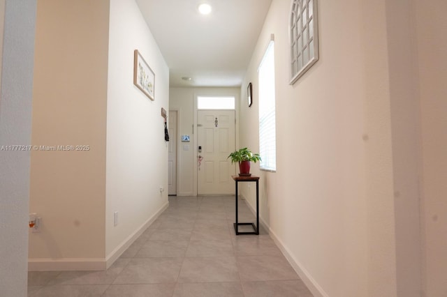 corridor featuring light tile patterned floors and baseboards