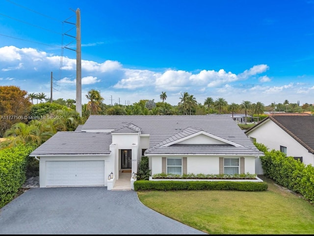 ranch-style home with a tiled roof, an attached garage, a front lawn, and stucco siding