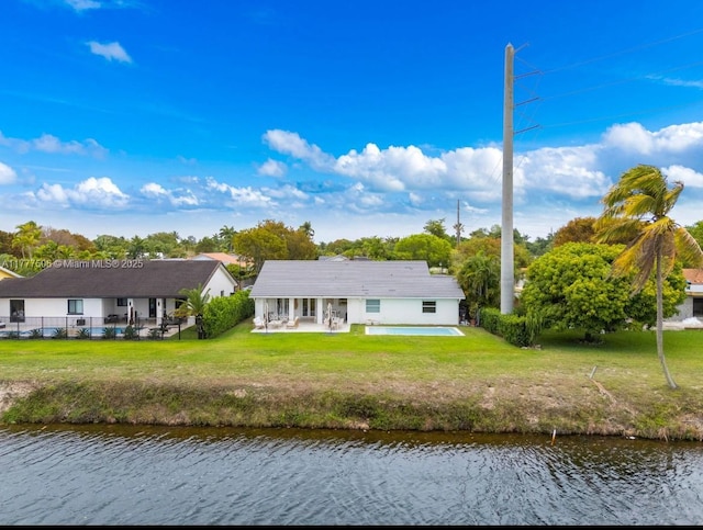 back of property featuring a water view, fence, a patio, and a lawn