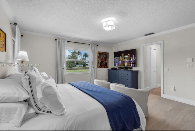 bedroom featuring crown molding, light wood-style flooring, and a textured ceiling