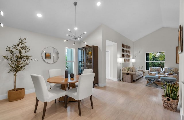 dining room with baseboards, light wood-type flooring, high vaulted ceiling, and an inviting chandelier