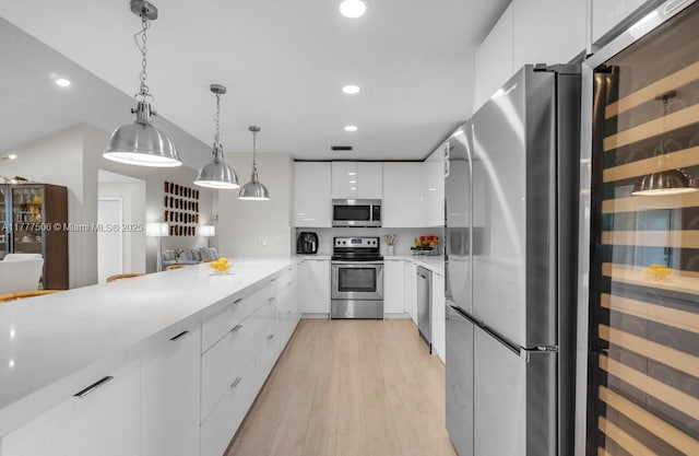 kitchen featuring light countertops, white cabinetry, modern cabinets, appliances with stainless steel finishes, and pendant lighting