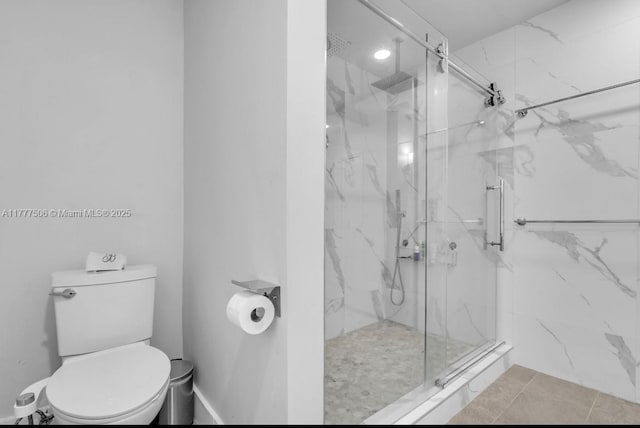 bathroom featuring a marble finish shower, toilet, and tile patterned flooring
