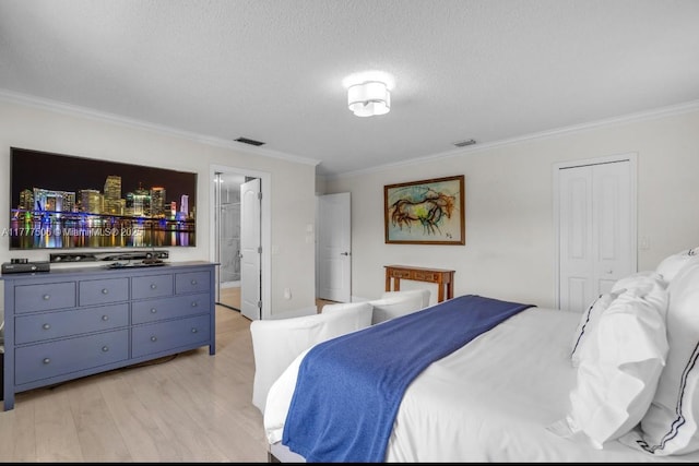 bedroom with ornamental molding, visible vents, light wood-style flooring, and a textured ceiling