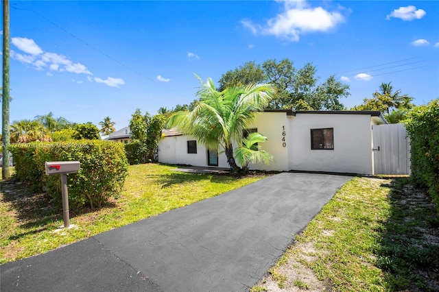 1640 NE 183rd St, North Miami Beach, FL 33179 - view of front of property with stucco siding, a front lawn, and asphalt driveway