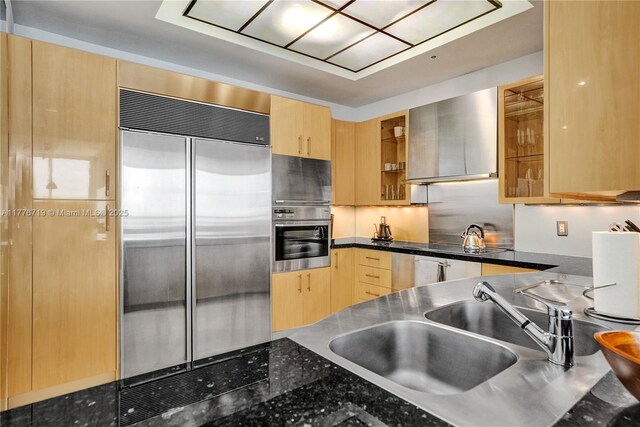 100 S Pointe Dr Unit 3102, Miami Beach, FL 33139 - kitchen with stainless steel appliances, wall chimney exhaust hood, light brown cabinetry, a sink, and glass insert cabinets