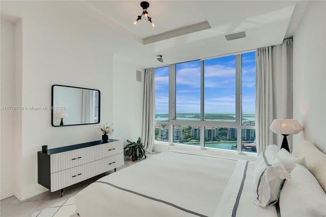 100 S Pointe Dr Unit 3102, Miami Beach, FL 33139 - bedroom featuring a water view, light tile patterned floors, a raised ceiling, a chandelier, and floor to ceiling windows