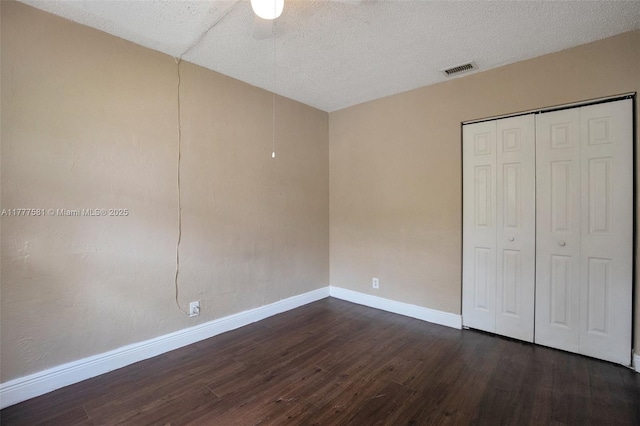 4061 N Dixie Hwy Unit 29, Oakland Park, FL 33334 - unfurnished bedroom with dark wood-style floors, baseboards, a closet, a ceiling fan, and a textured ceiling