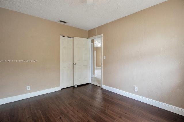 4061 N Dixie Hwy Unit 29, Oakland Park, FL 33334 - unfurnished bedroom with dark wood-style floors, baseboards, a closet, and a textured ceiling