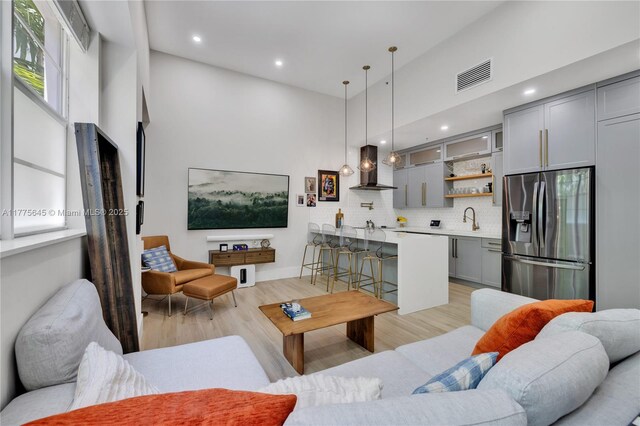 living area featuring a high ceiling, light wood-style floors, visible vents, and recessed lighting