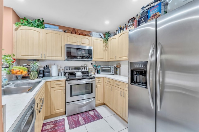 kitchen featuring light brown cabinets, light countertops, stainless steel appliances, and light tile patterned floors