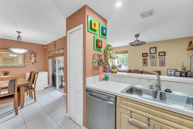 kitchen featuring light tile patterned flooring, light countertops, a sink, stainless steel dishwasher, and decorative light fixtures