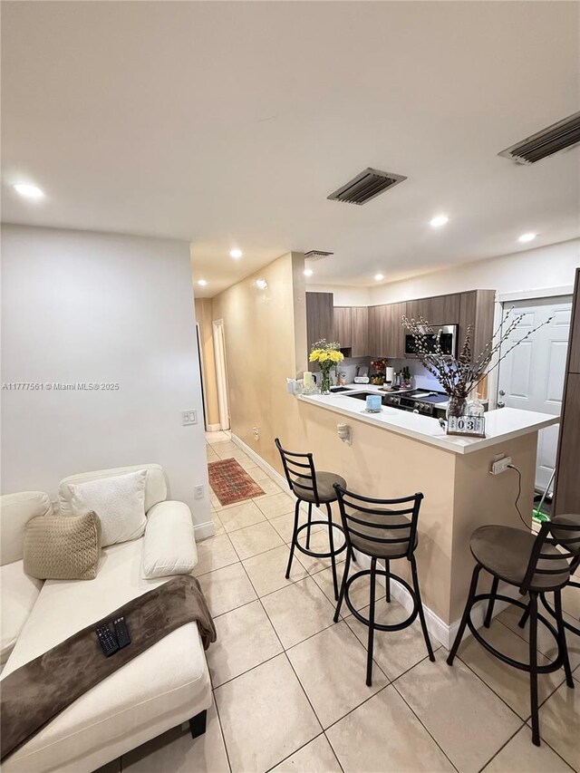 4441 SW 33rd Dr, West Park, FL 33023 - kitchen with a breakfast bar, a peninsula, dark brown cabinetry, light countertops, and light tile patterned floors