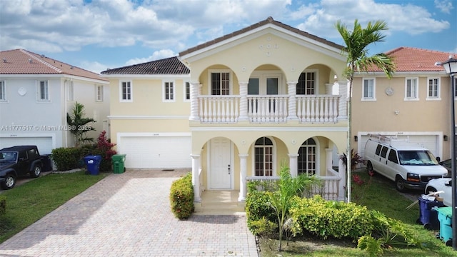 mediterranean / spanish-style house featuring a tile roof, stucco siding, an attached garage, decorative driveway, and covered porch