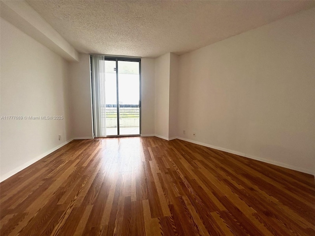 empty room with baseboards, floor to ceiling windows, a textured ceiling, and wood finished floors