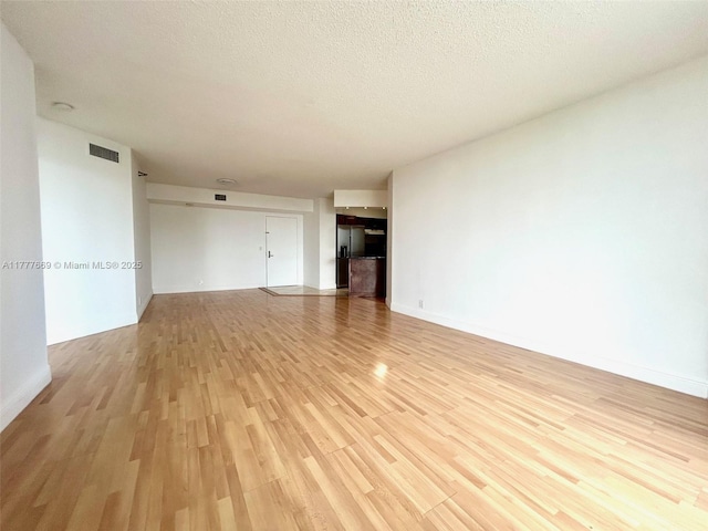 unfurnished living room featuring a textured ceiling, visible vents, and light wood-type flooring