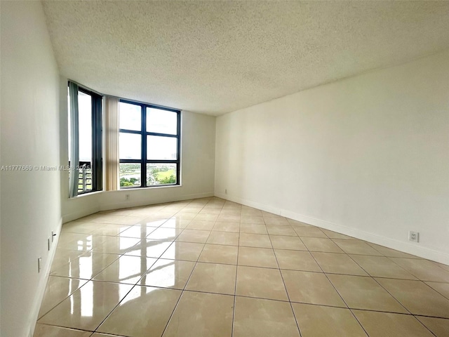 spare room featuring baseboards, a textured ceiling, and tile patterned floors
