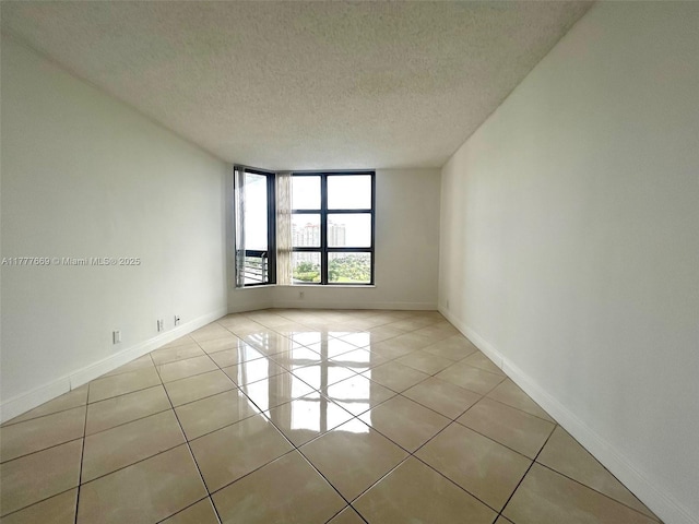 spare room with a textured ceiling, baseboards, and light tile patterned floors