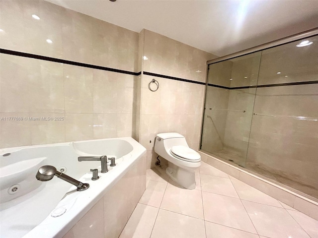 bathroom with tile walls, a tub with jets, tile patterned floors, toilet, and a stall shower