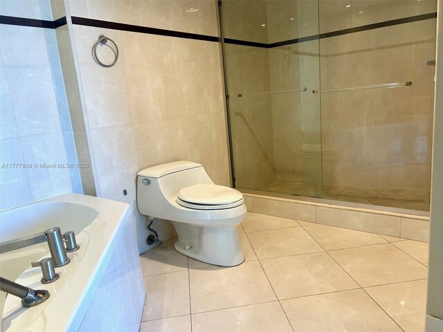 full bathroom with a shower stall, tile patterned floors, toilet, and tile walls
