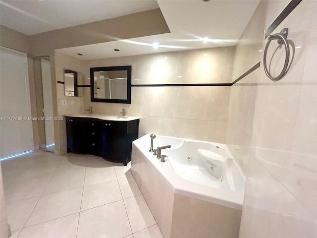 full bath with tile walls, a tub with jets, tile patterned floors, a sink, and double vanity