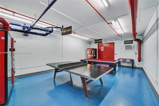 recreation room featuring speckled floor and a wall unit AC