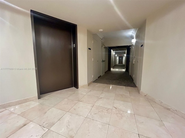 hall featuring elevator and baseboards