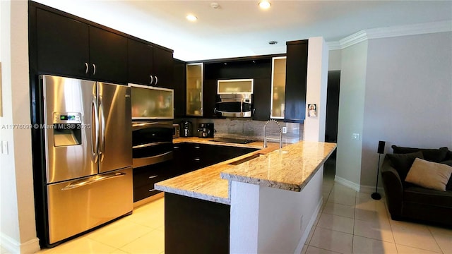kitchen featuring stainless steel appliances, a peninsula, dark cabinetry, glass insert cabinets, and crown molding