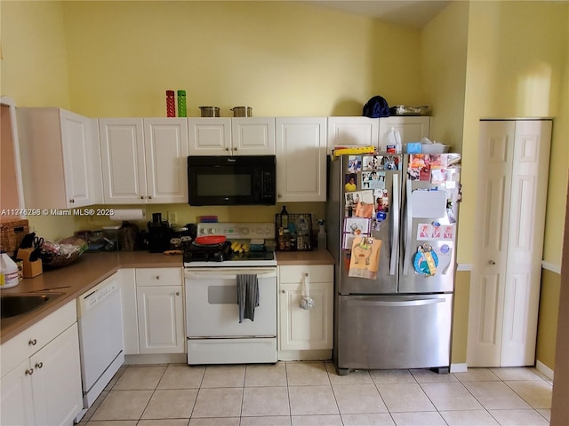 kitchen with a sink, light tile patterned floors, white cabinets, and white appliances