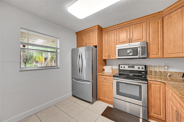 1820 SW 81st Ave Unit 3300, North Lauderdale, FL 33068 - kitchen with baseboards, a textured ceiling, stainless steel appliances, light tile patterned flooring, and light stone counters