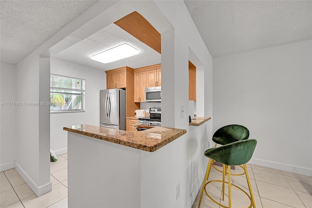 1820 SW 81st Ave Unit 3300, North Lauderdale, FL 33068 - kitchen featuring baseboards, appliances with stainless steel finishes, a peninsula, a textured ceiling, and light tile patterned flooring