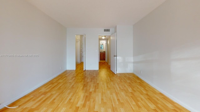 empty room featuring visible vents, light wood-style flooring, and baseboards