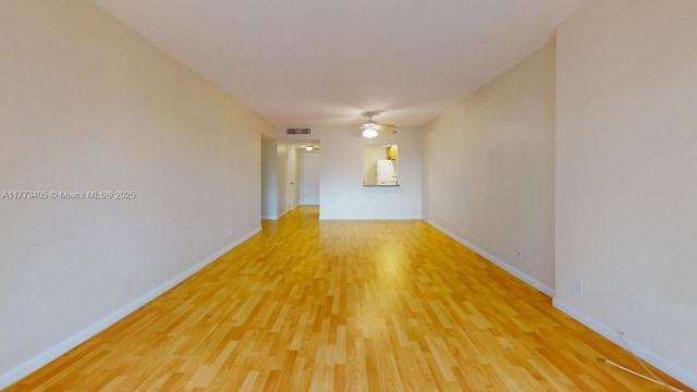 spare room featuring baseboards, visible vents, a ceiling fan, and light wood finished floors