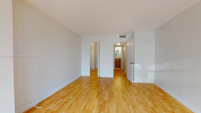 empty room with visible vents, light wood-style flooring, and baseboards