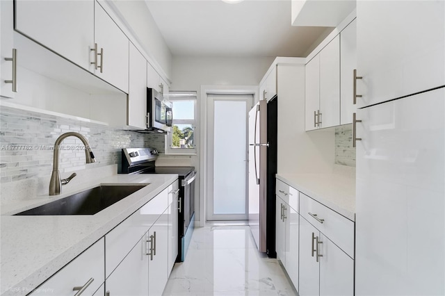 641 Espanola Way Unit 35, Miami Beach, FL 33139 - kitchen featuring appliances with stainless steel finishes, a sink, light marble finish flooring, tasteful backsplash, and white cabinetry