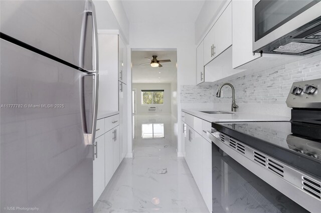641 Espanola Way Unit 35, Miami Beach, FL 33139 - kitchen featuring appliances with stainless steel finishes, a sink, ceiling fan, white cabinetry, and tasteful backsplash