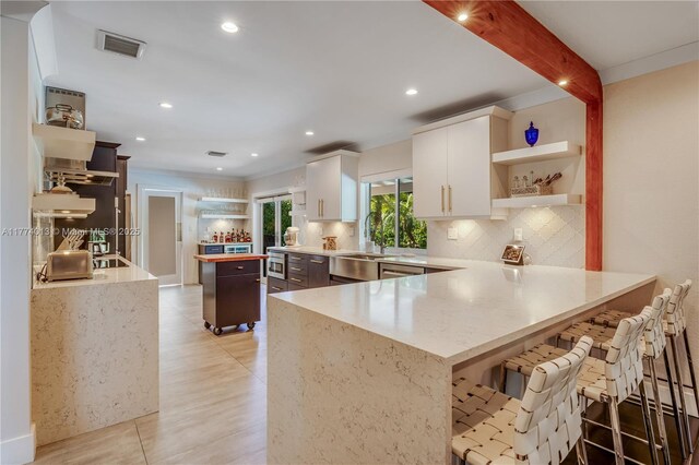 7465 SW 159th Ter, Palmetto Bay, FL 33157 - kitchen featuring white cabinetry, tasteful backsplash, open shelves, visible vents, and a peninsula