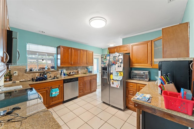 6930 SW 5th St, Pembroke Pines, FL 33023 - kitchen with stainless steel appliances, backsplash, brown cabinets, light tile patterned floors, and light stone counters