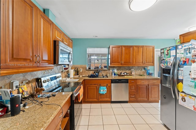 6930 SW 5th St, Pembroke Pines, FL 33023 - kitchen with stainless steel appliances, brown cabinets, decorative backsplash, light tile patterned floors, and light stone countertops