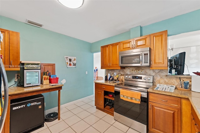 6930 SW 5th St, Pembroke Pines, FL 33023 - kitchen with brown cabinets, visible vents, baseboards, appliances with stainless steel finishes, and tasteful backsplash