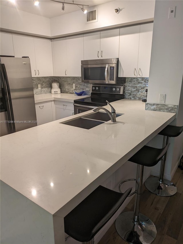 19901 E Country Club Dr Unit 2305, Aventura, FL 33180 - kitchen with white cabinetry, stainless steel appliances, a breakfast bar, decorative backsplash, and a sink