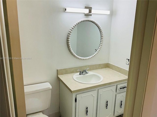half bath featuring vanity and toilet