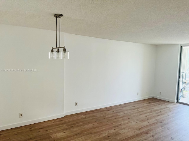 unfurnished dining area featuring baseboards, wood finished floors, and a textured ceiling