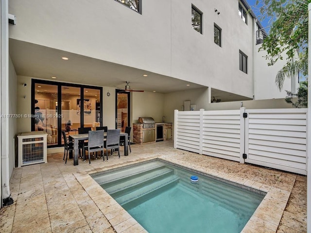 view of pool featuring fence, exterior kitchen, outdoor dining space, a patio, and grilling area