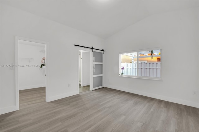 17663 SW 5th St, Pembroke Pines, FL 33029 - unfurnished bedroom featuring a barn door, baseboards, wood finished floors, a spacious closet, and vaulted ceiling