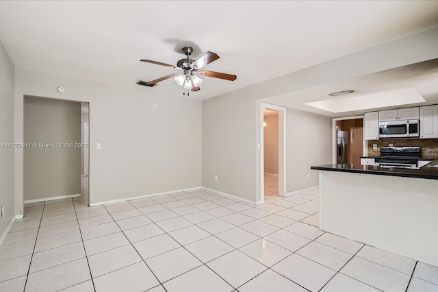 kitchen featuring a ceiling fan, dark countertops, stainless steel appliances, backsplash, and light tile patterned flooring