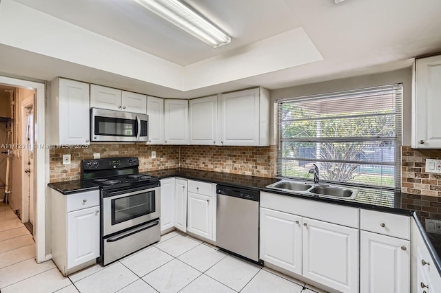 kitchen with tasteful backsplash, dark countertops, a sink, and appliances with stainless steel finishes