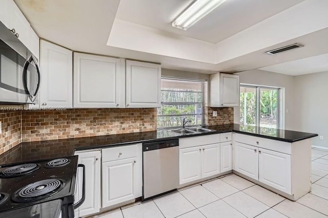 kitchen with a peninsula, backsplash, visible vents, stainless steel appliances, and a sink