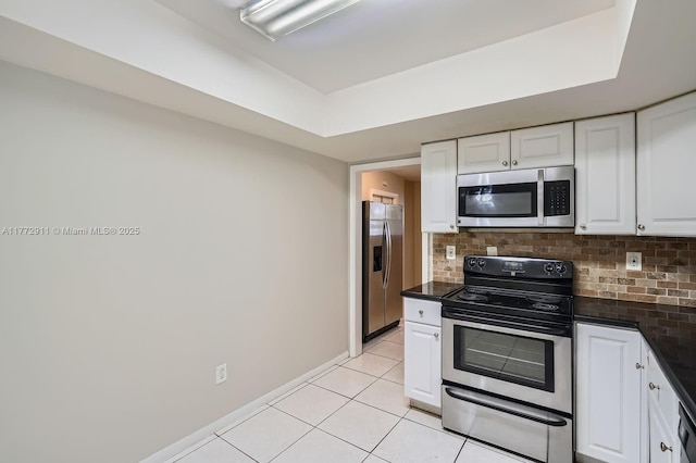 kitchen with light tile patterned floors, white cabinetry, dark countertops, stainless steel appliances, and backsplash