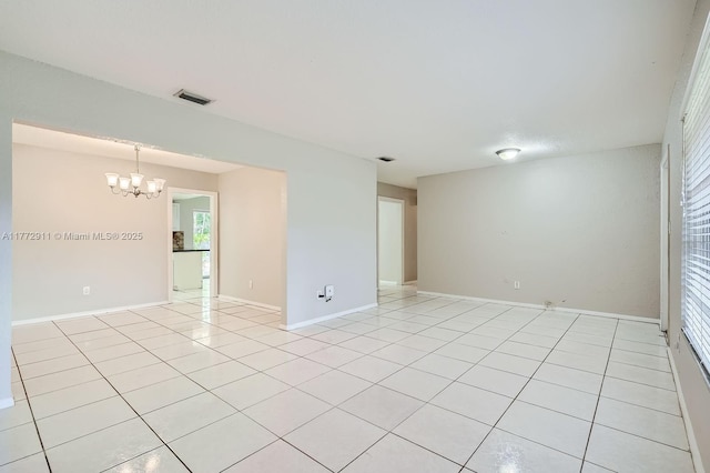 spare room with a chandelier, light tile patterned floors, baseboards, and visible vents
